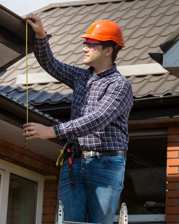 professional worker measuring height of roof with tape Portrait of professional worker measuring height of roof with tape