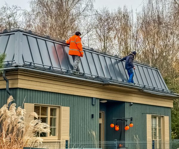 Workers on Roof of Cozy House with Decorations Outdoors. High quality photo